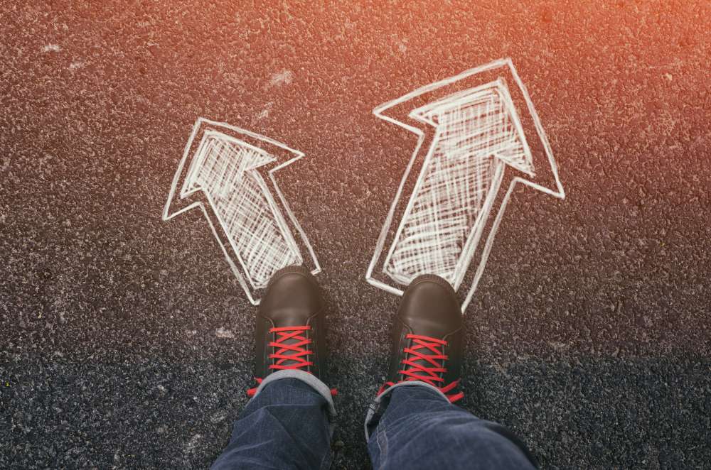中国で2本の矢印が描かれた道路に立つ人の足。