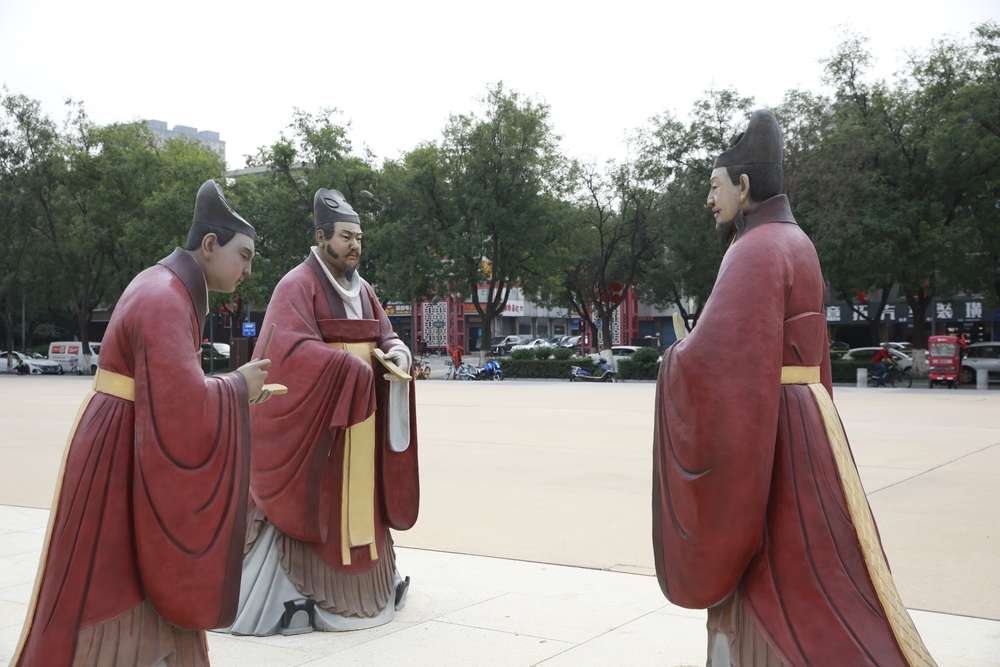 3 人の中国男性が紫色の長靴を着ている像。