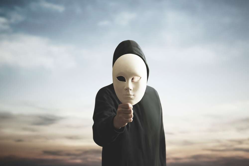 黒いパーカーを着た人物が曇り空を背景にカメラに向かって白いマスクを掲げており、伝統的な中国オペラを思わせる神秘的な雰囲気を醸し出している。