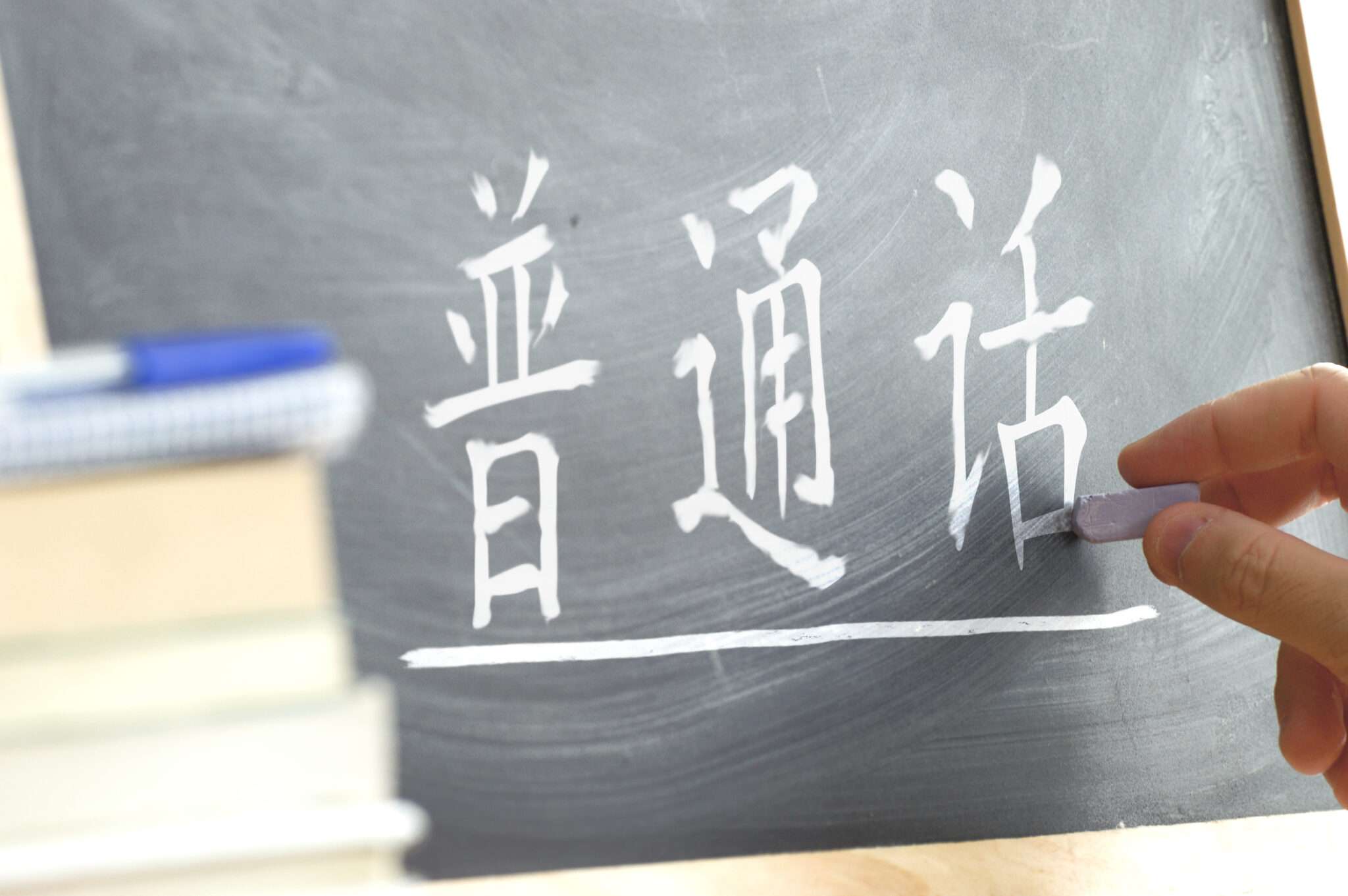 中国で黒板に漢字を書く人。