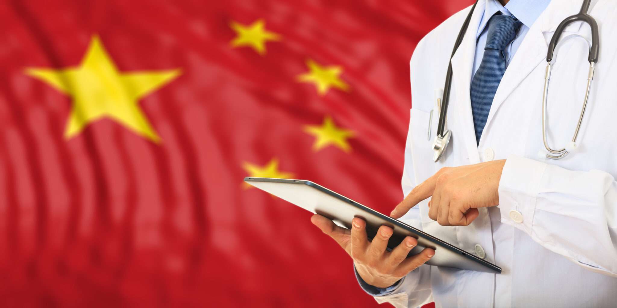 中国の国旗の前でタブレットと聴診器を誇らしげに持つ医師。
