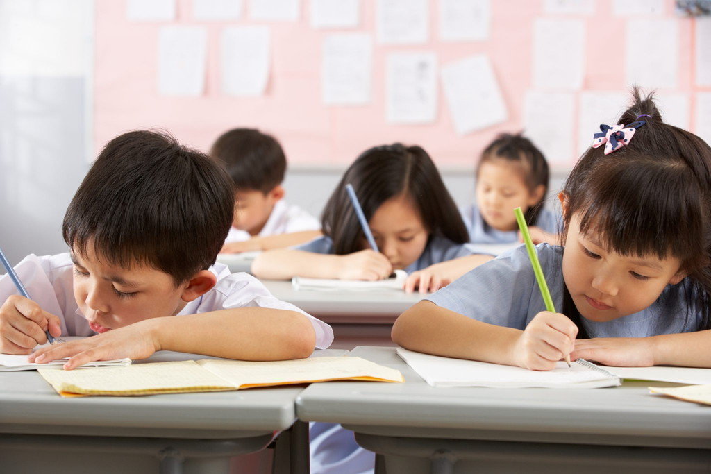 中国語教室の机に向かって書き物をする子供たちのグループ。