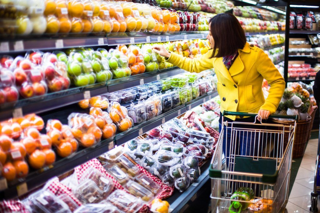 黄色いジャケットを着た女性が中国食材店で買い物をしている。