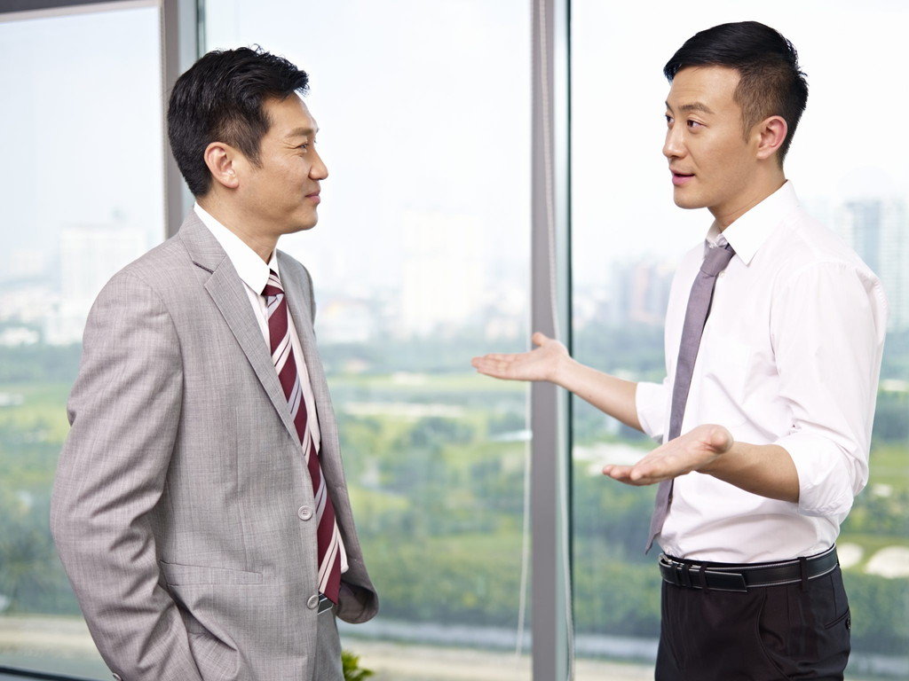 窓の前で話している 2 人の中国人ビジネスマン。