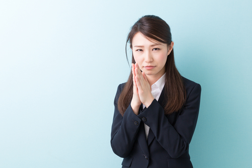 顔に手を当ててイライラやストレスを表現する日本のビジネスウーマン。