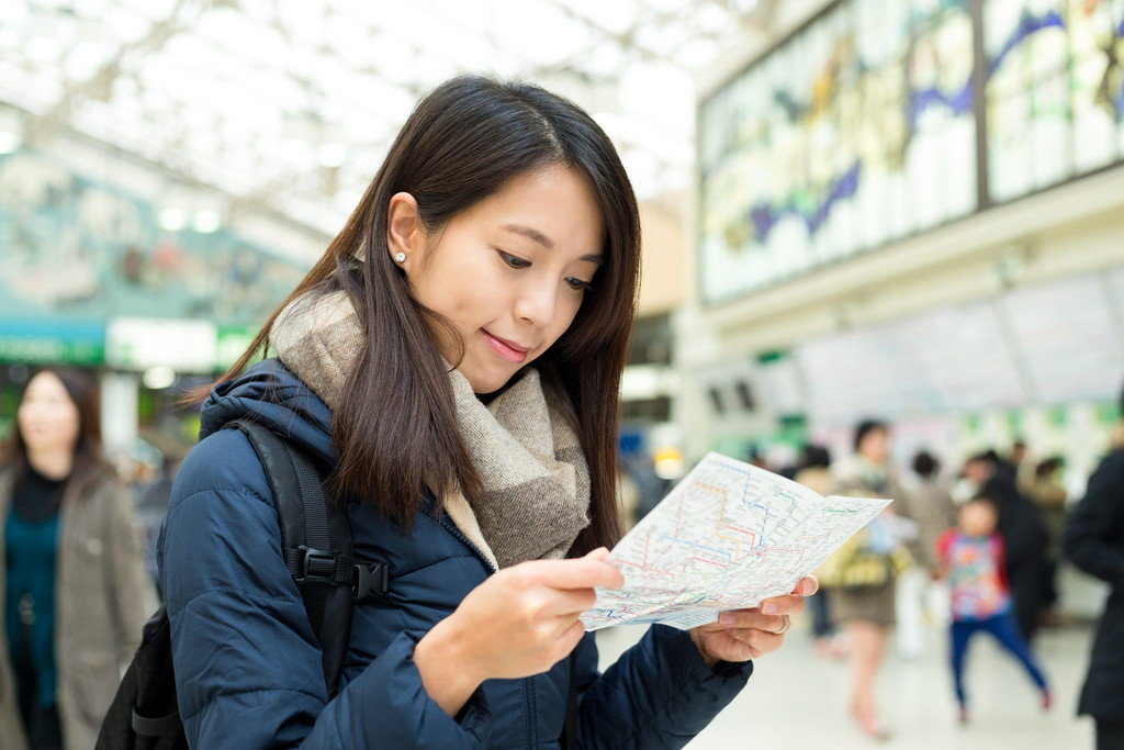 中国の駅で地図を見ているアジア人の女性。