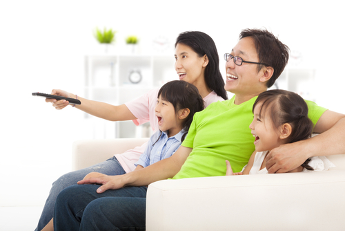 ソファに座ってテレビを見ている中国人の家族。