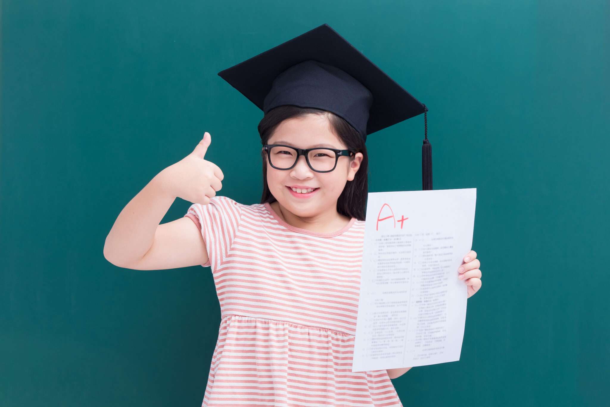 卒業証書を持ち親指を立てる若い中国人の女の子。