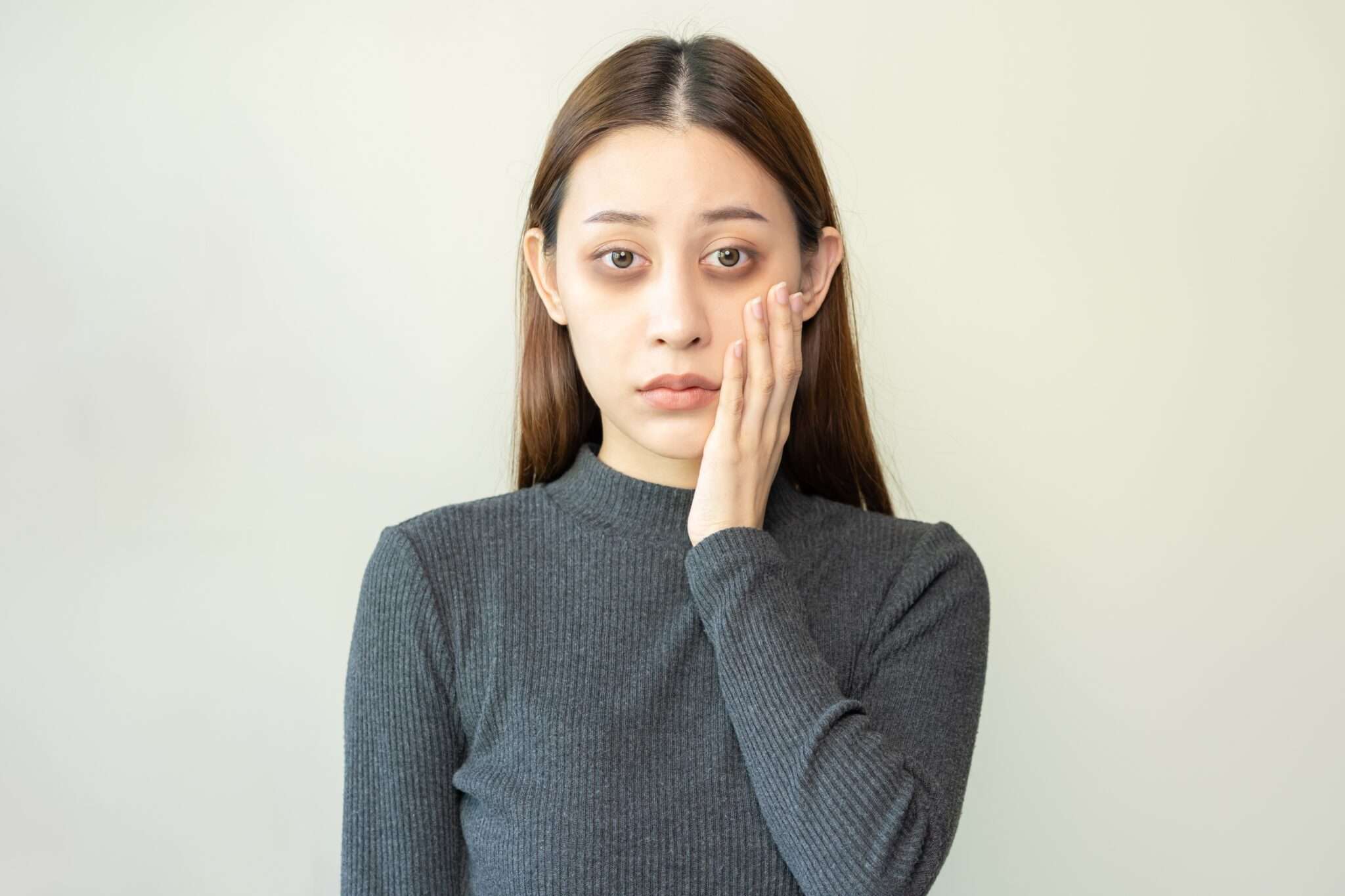 顔に手を当てた中国出身の若いアジア人女性。