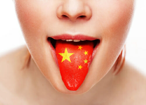 中国国旗を誇らしげに舌に掲げる女性。