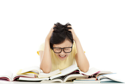 女の子が本の山の上に座って、頭を抱えて度臺学业の挑戦について熟考しています。