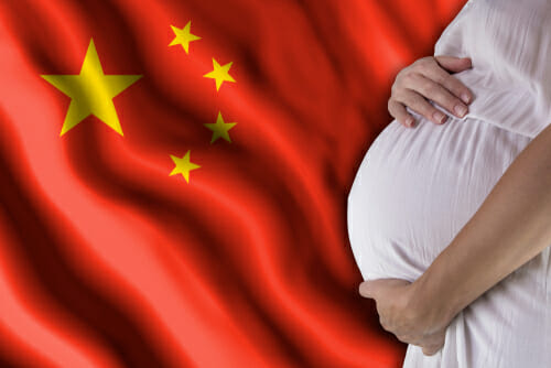 中国の国旗の前に立つ妊婦。