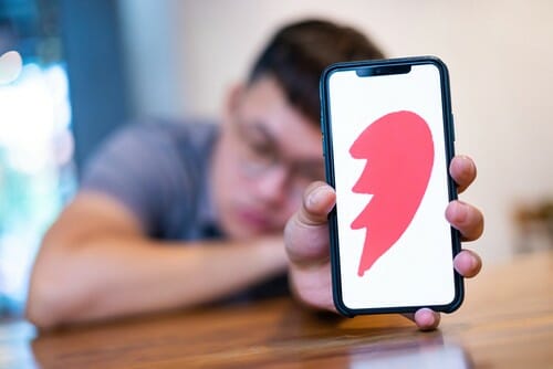 愛の象徴としてハートのついた携帯電話を掲げる男性。