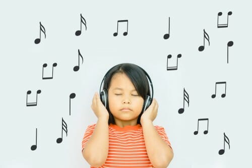 一人の小さな女の子がイヤホンを着けて音を鳴らしています。