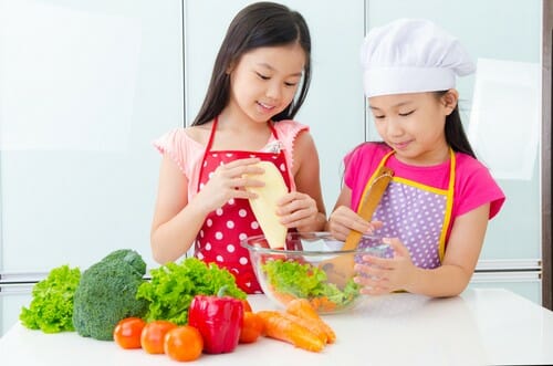 2 人の若い女の子が中国のキッチンで野菜を準備しています。