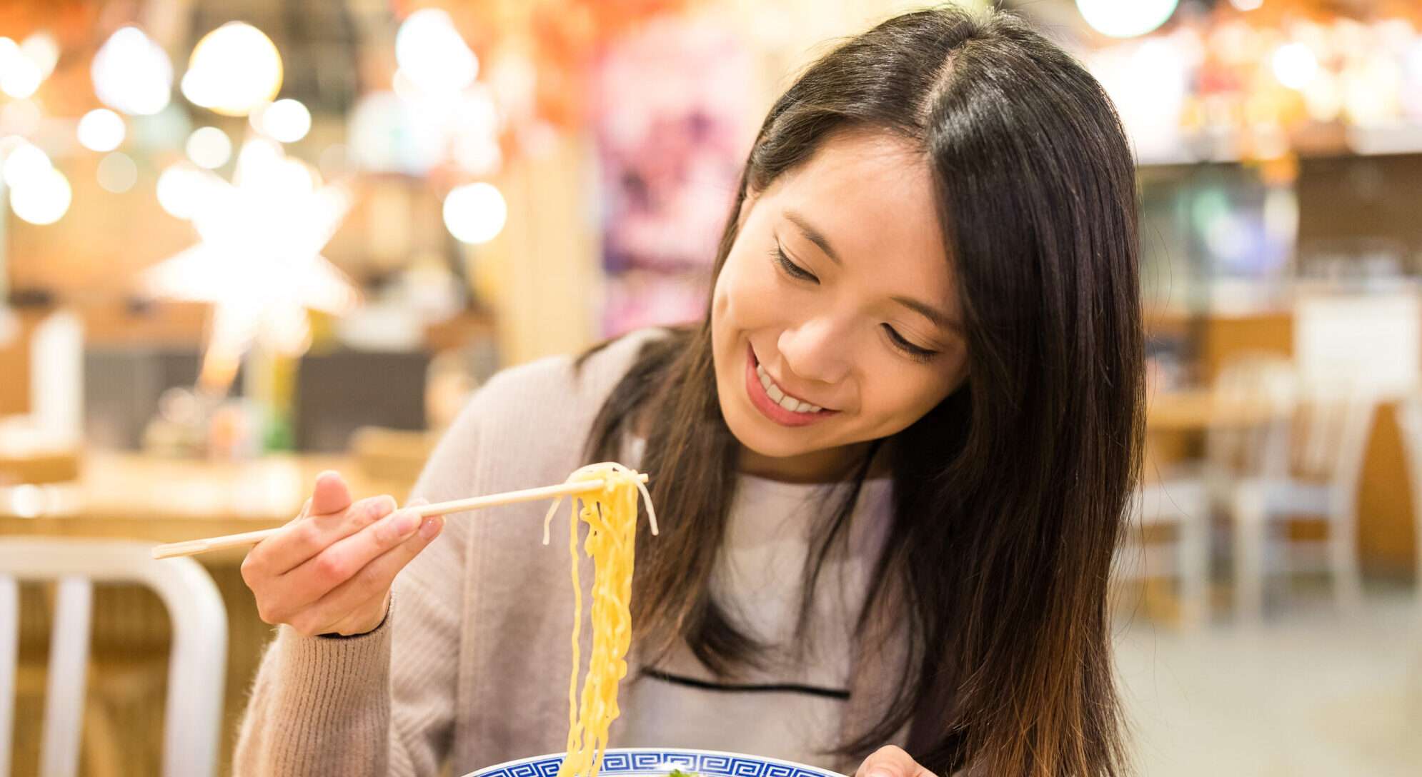 女性が中華料理店で麺を食べています。
