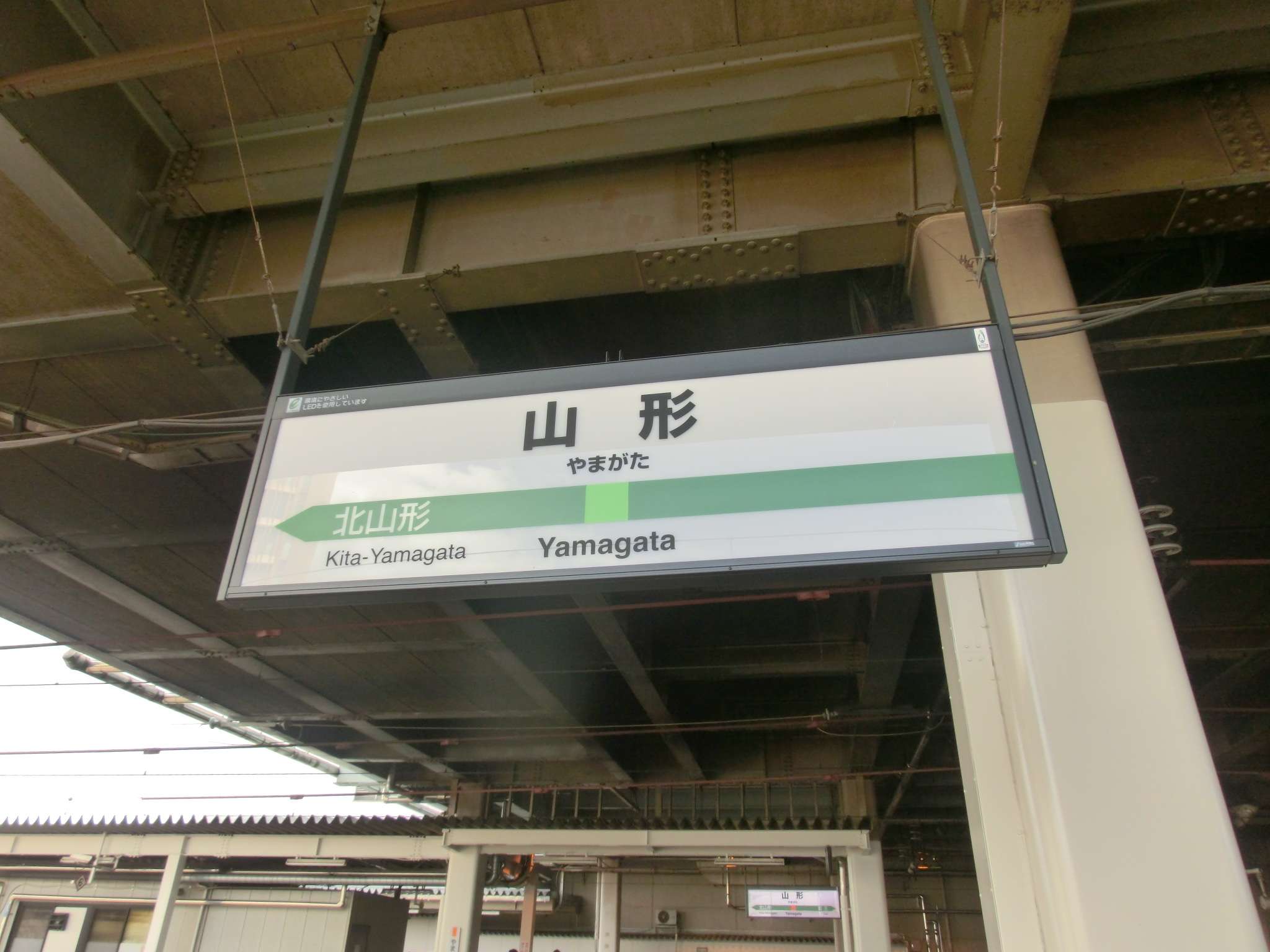 駅のホームには「山形」「北山形」と方向矢印が大きく書かれた標識が設置されている。近くには、山形・米沢エリアで受けられる中国語教室の広告が掲載されています。