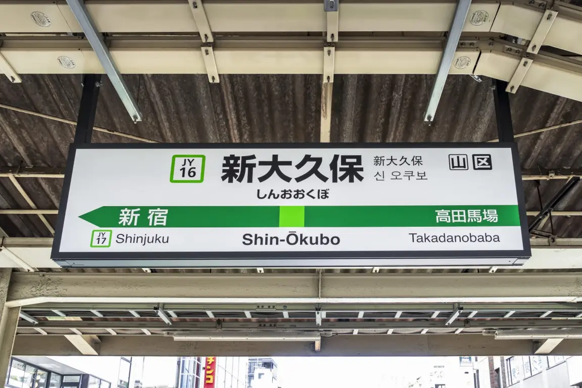 新大久保の駅ホームには、新宿と高田馬場への案内が日本語、英語、韓国語で表示されている。.