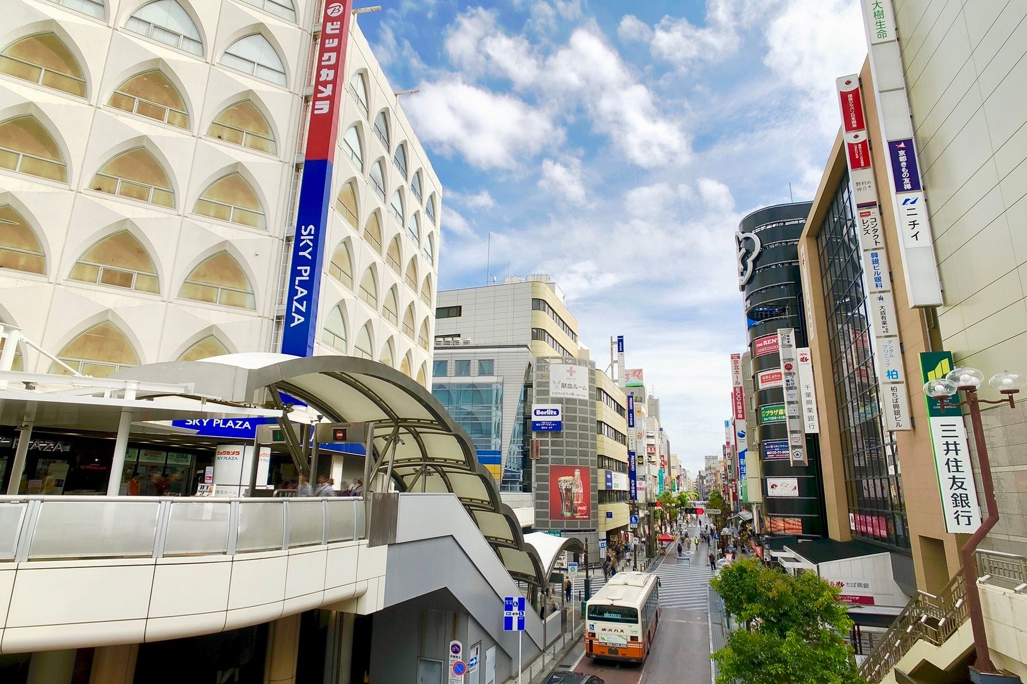 様々な店、日本語の看板、バス、そして歩く人々。.