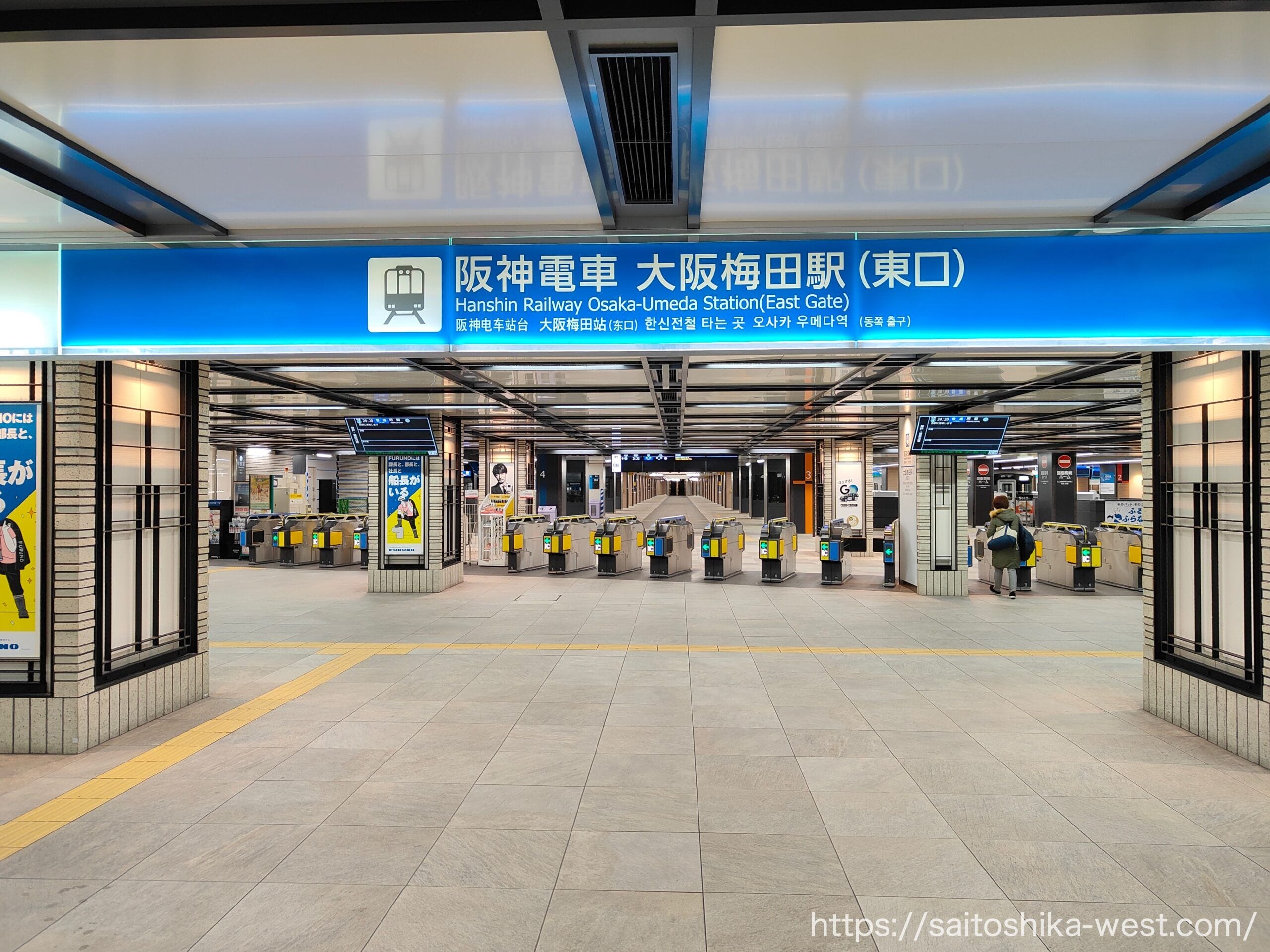 阪神電鉄大阪梅田駅東口の改札口。日本語と英語の頭上サインと自動バリアが見える。.