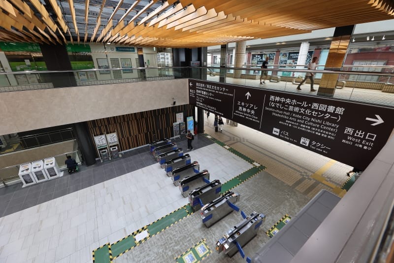 改札口、日本語と英語の頭上看板、木製の天井が特徴的な日本の近代的な駅の内部。駅構内を歩く人々。.