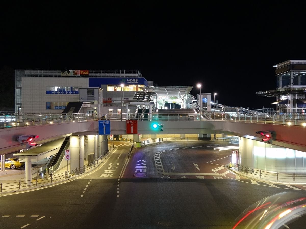 夜間の明るく照らされた近代的な都市交通の拠点。高架道路、案内標識、そして入り口がライトアップされたメインビルが特徴である。.